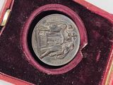 a silver coin in a red case on a white surface