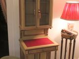 a wooden cabinet with a red cushion on top of it next to a lamp