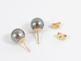 two pairs of black pearls and gold stud earrings on a white surface