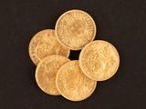 cinq pièces d'or sont disposées sur une surface noire