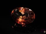 a close up of an orange diamond on a black surface