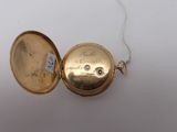 a gold pocket watch with a chain on a white surface