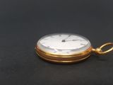a close up of a gold pocket watch on a black surface