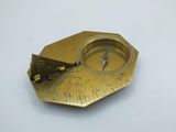 a small brass compass on a white surface