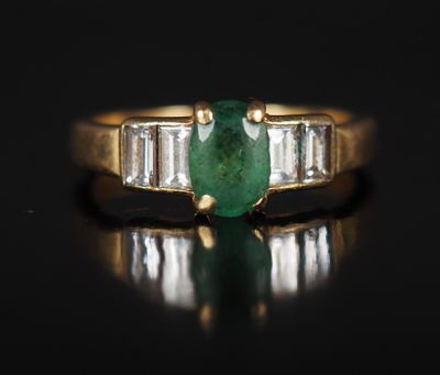 une bague en émeraude et diamant sur une surface noire