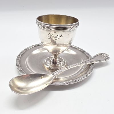 une tasse et une soucoupe anciennes en argent, avec une cuillère posée sur la soucoupe