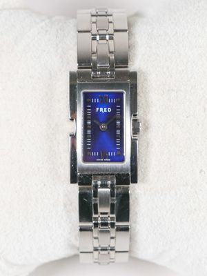 une montre en argent au cadran bleu posée sur une serviette blanche