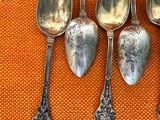 four spoons are sitting on an orange cloth with a silver spoon in the middle of them
