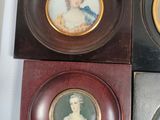 four framed miniature portraits of women are displayed in a display case