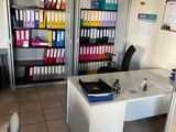 an office with a desk and a lot of folders on the shelves