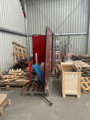 Plusieurs palettes de bois sont empilées dans un entrepôt dont la porte est rouge.