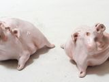 two small pink pig figurines sitting on a table