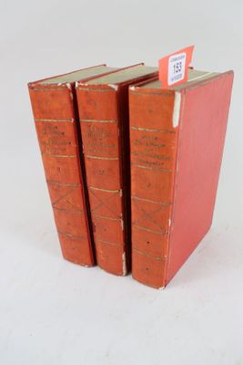 trois livres rouges sont empilés sur une surface blanche