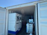 a container with a refrigerator inside of it in the middle of a lot