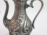 a silver tea pot sitting on a table next to a glass