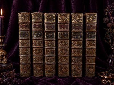 five old books on a table with a candle on it