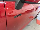 a close up of a red car door with a sticker on it