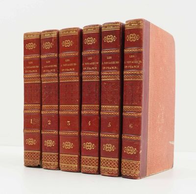 six livres rouges alignés sur une surface blanche