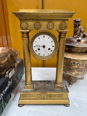 a gold clock sitting on top of a table next to other items