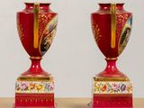 two red vases sitting on a table with gold trimming
