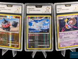 trois types différents de cartes Pokémon dans des pochettes en plastique, sur fond noir