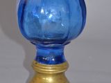 a blue glass vase with a gold base on a table