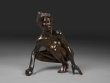 une statue en bronze représentant une femme assise à genoux