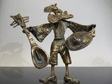 figurine en bronze représentant un homme jouant d'un instrument de musique, posée sur une surface noire