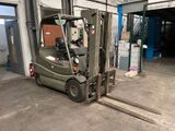 a green fork truck parked in a garage next to a building