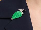 a close up of a woman wearing a green broocher