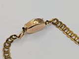 an image of a gold chain bracelet with a coin on it