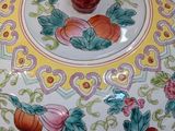 a decorative bowl with fruit and flowers on it