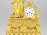 une horloge en or surmontée d'une femme debout