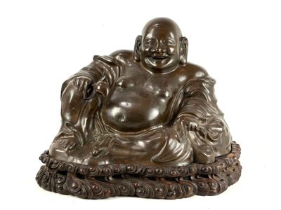 statue of a laughing buddha sitting on a cushion on a white surface
