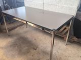 une table aux pieds chromés et au plateau blanc, placée au milieu d'une pièce