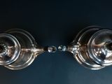 two silver lamps that are on a blue wall