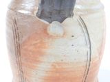 a brown vase with a black handle on a white surface