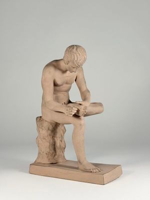 statue of a man sitting on a rock with his legs crossed