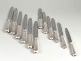 six knives are lined up in a row on a white surface