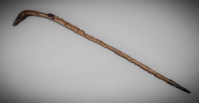 a close up of a cane with a wooden handle on a white surface
