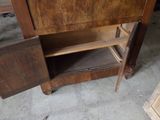 une armoire en bois dont la porte est ouverte et repose sur le sol