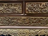 a wooden chest of drawers with carvings on it