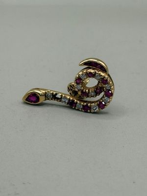 un gros plan d'une boucle d'oreille en diamant rouge et blanc posée sur une surface blanche