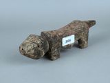 une vieille figurine de chien en bois à laquelle est accrochée une étiquette