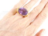 someone is holding a ring with a purple stone on it