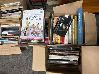 a box full of books on the floor next to a pile of other books