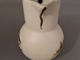 a small white vase with a brown design on it