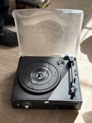 a record player sitting on the floor next to a pair of shoes