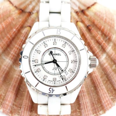 a white watch sitting on top of a seashell