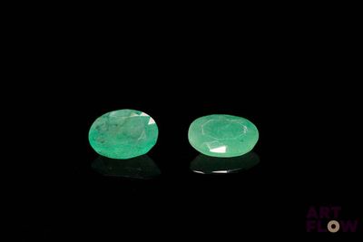 a pair of green emeralds on a black surface